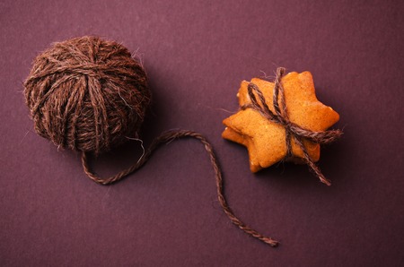 Homemade rye cookies star shaped stack tied with brown rope on dark background. rope skein lying nearの写真素材
