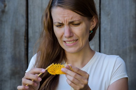 girl can not knit with needles and yellow yarn and she is very upsetの写真素材