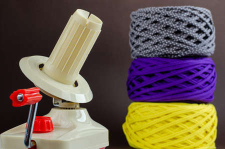 hand plastic wool winder, yellow, purple, gray yarn balls, brown background. Knitting, crochet,...