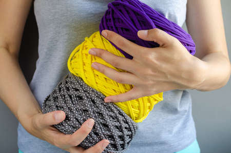 female hands holding big purple, yellow and gray t-shirt yarn balls. Handmade, craft, recycle, eco...