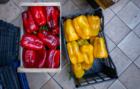 Fresh red and yellow bell peppers displayed in baskets outdoors.の写真素材
