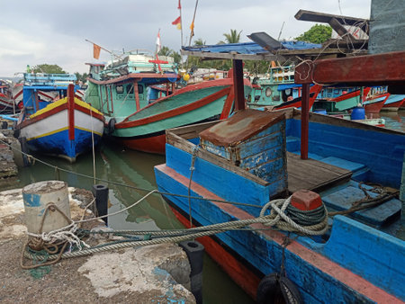 Fishing wooden boat is leaning in the harbor and anchoredの写真素材