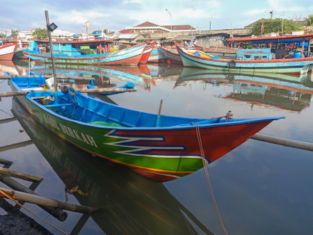 Fishing wooden boat is leaning in the harbor and anchored. Marine and maritime fisheries industry in Indonesia and Southeast Asiaの写真素材