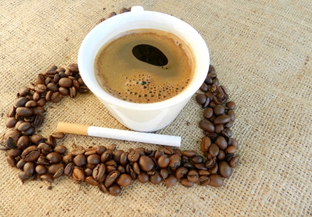 Cup of coffee with cigarette and coffee beans on  sackingの写真素材