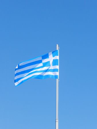 Greek flag in the wind against the blue skyの写真素材
