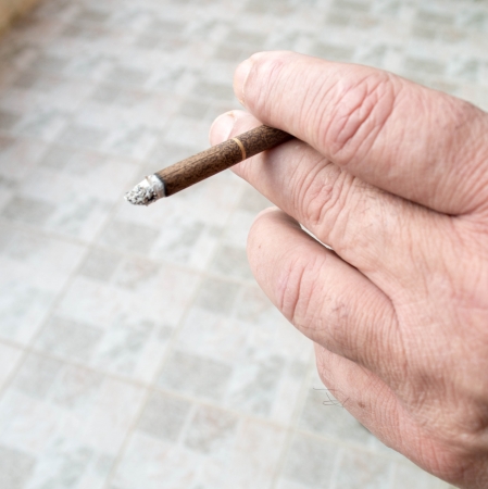 man hand holding a black cigarette with smokeの写真素材