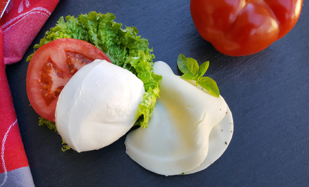 Mozzarella cheese with tomato on dark stone backgroundの写真素材