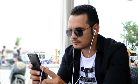 Happy young man using his smart phone outdoorの写真素材