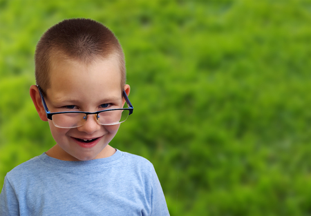 Adorable little boy looking over glasses and smilingの写真素材