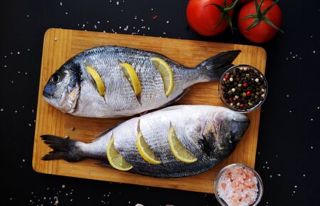 Two ready to cook fresh dorada fish decorated with lemon の写真素材