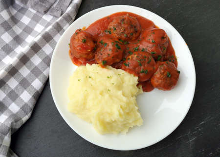 Delicious meatballs in tomato sauce with mashed potatoes, served on white plate