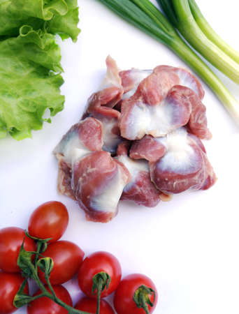 Raw uncooked chicken gizzards (stomachs), with fresh vegetables on white background