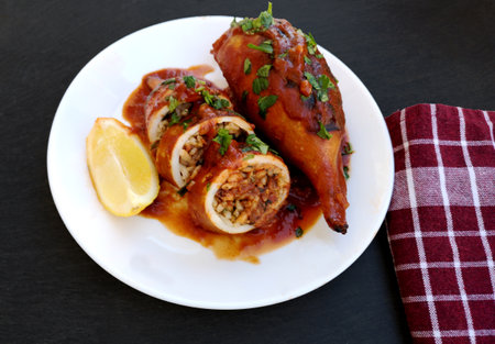 A plate of tasty squid stuffed with rice and vegetables in tomato sauceの写真素材