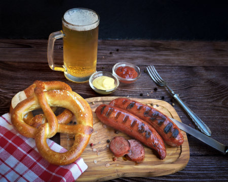 Oktoberfest background with bavarian sausages, pretzels and beer on wooden tableの写真素材