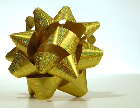 a close up of a christmas gift bow. It is gold with many color highlights shiningの写真素材
