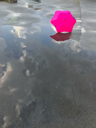 umbrella and reflection of the sky in a puddle after a rainの写真素材