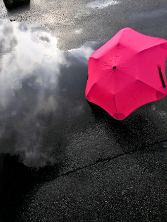 umbrella and reflection of the sky in a puddle after a rainの写真素材
