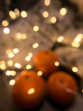 orange mandarins and garlands on a cold winter evening bokeh effectの写真素材
