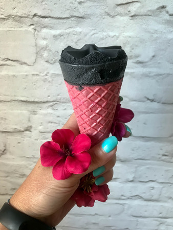 black ice cream in a pink cup of a handの写真素材
