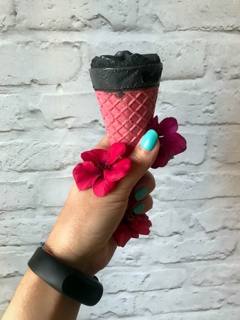 black ice cream in a pink cup of a handの写真素材