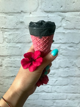 black ice cream in a pink cup of a handの写真素材