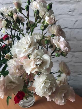 white and red roses in a vase on a tableの写真素材