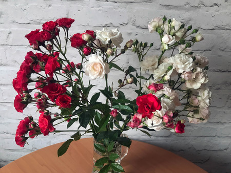 white and red roses in a vase on a tableの写真素材
