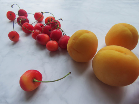 apricots and sweet cherries beautifully lie on the tableの写真素材