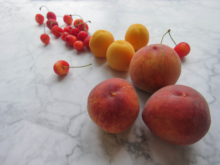 Peaches, apricots and sweet cherries beautifully lie on the tableの写真素材