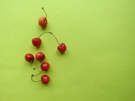 red cherries beautifully lie on a yellow tableの写真素材