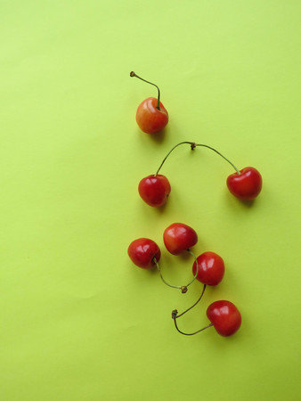 red cherries beautifully lie on a yellow tableの写真素材