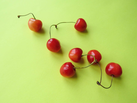 red cherries beautifully lie on a yellow tableの写真素材