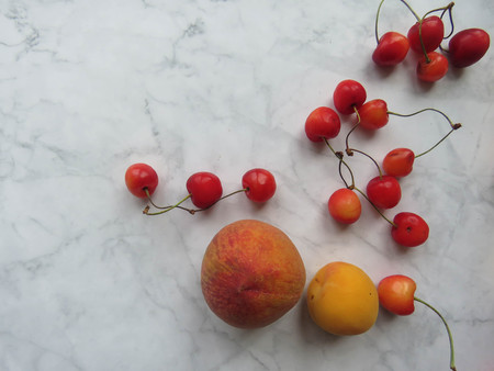 Peaches, apricots and sweet cherries beautifully lie on the tableの写真素材