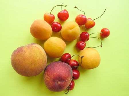 Peaches, apricots and sweet cherries beautifully lie on the tableの写真素材