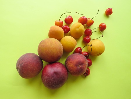 Peaches, apricots and sweet cherries beautifully lie on the tableの写真素材