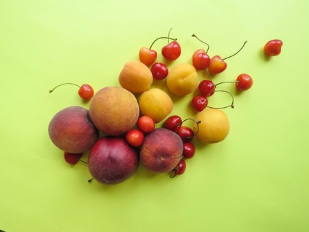 Peaches, apricots and sweet cherries beautifully lie on the tableの写真素材