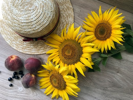 Straw Hat, peaches, sunflowers and current on the tableの写真素材