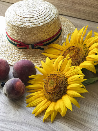 Straw Hat, peaches, sunflowers and current on the tableの写真素材