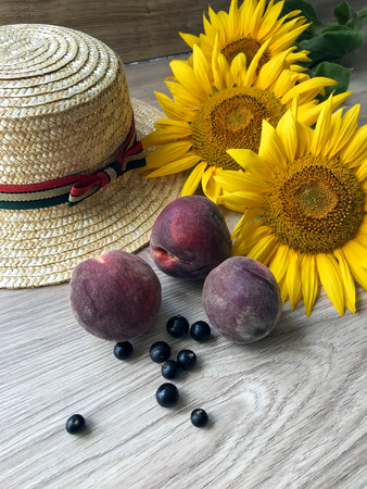 Straw Hat, peaches, sunflowers and current on the tableの写真素材