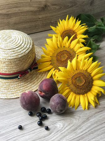 Straw Hat, peaches, sunflowers and current on the tableの写真素材