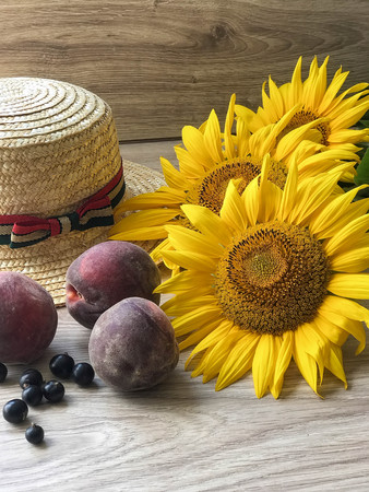 Straw Hat, peaches, sunflowers and current on the tableの写真素材