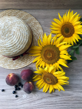 Straw Hat, peaches, sunflowers and current on the tableの写真素材