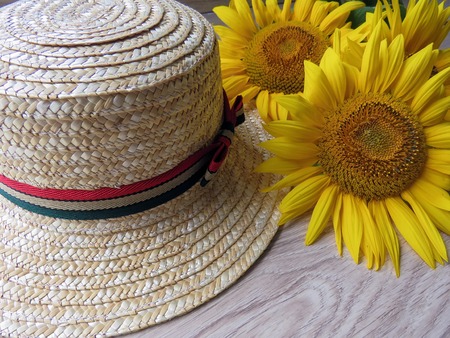 The straw hat and sunflowers on wooden backgroundの写真素材
