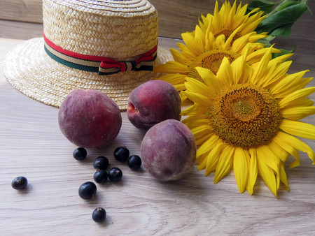Straw Hat, peaches, sunflowers and current on the tableの写真素材