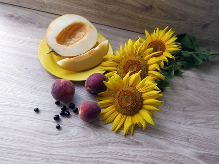 The melon in a plate on a table with sunflowersの写真素材