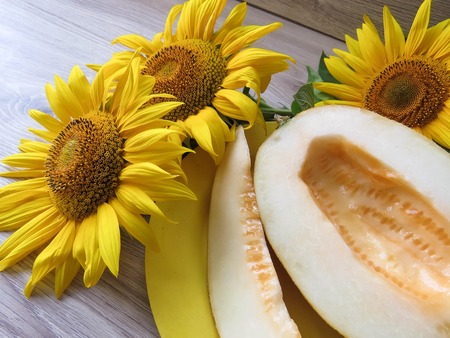 The melon in a plate on a table with sunflowersの写真素材
