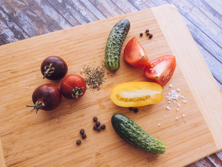 red and yellow tomatoes sliced and cucumber on a wooden board. healthy eating. eco-friendly products. Organic Food. Style Top View Group Objectsの写真素材