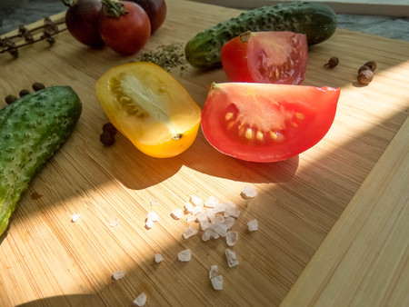 red and yellow tomatoes sliced and cucumber on a wooden board. healthy eating. eco-friendly products. Organic Food. Style Top View Group Objectsの写真素材