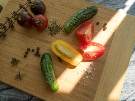 red and yellow tomatoes sliced and cucumber on a wooden board. healthy eating. eco-friendly products. Organic Food. Style Top View Group Objectsの写真素材