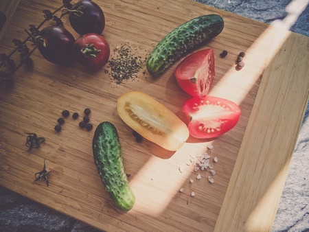 red and yellow tomatoes sliced and cucumber on a wooden board. healthy eating. eco-friendly products. Organic Food. Style Top View Group Objectsの写真素材